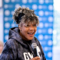 Woman standing up smiling as she hold microphone